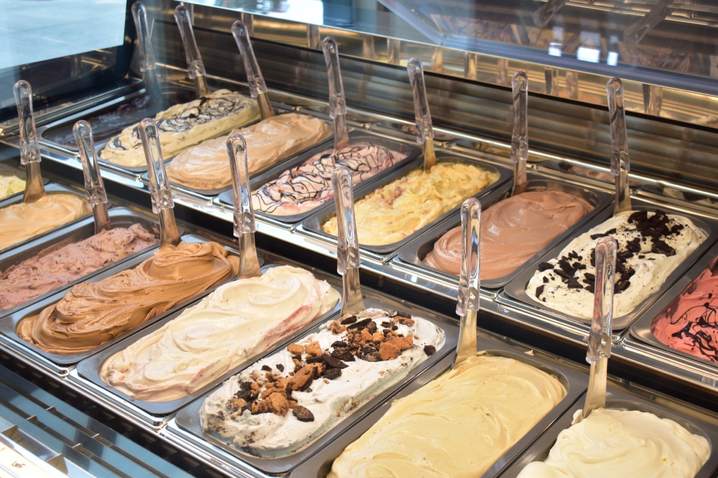 Full gelato display case with many flavors